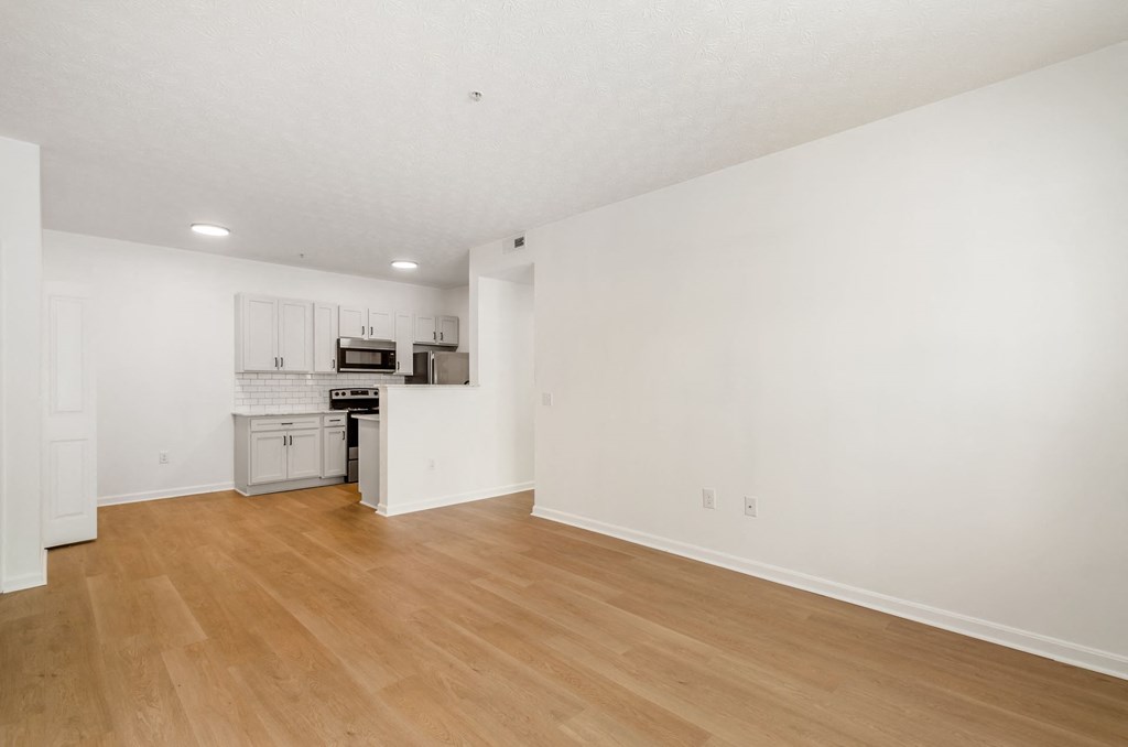 an empty living room and kitchen with white walls and wood floors at Prescott Place, Columbus, OH, 43235