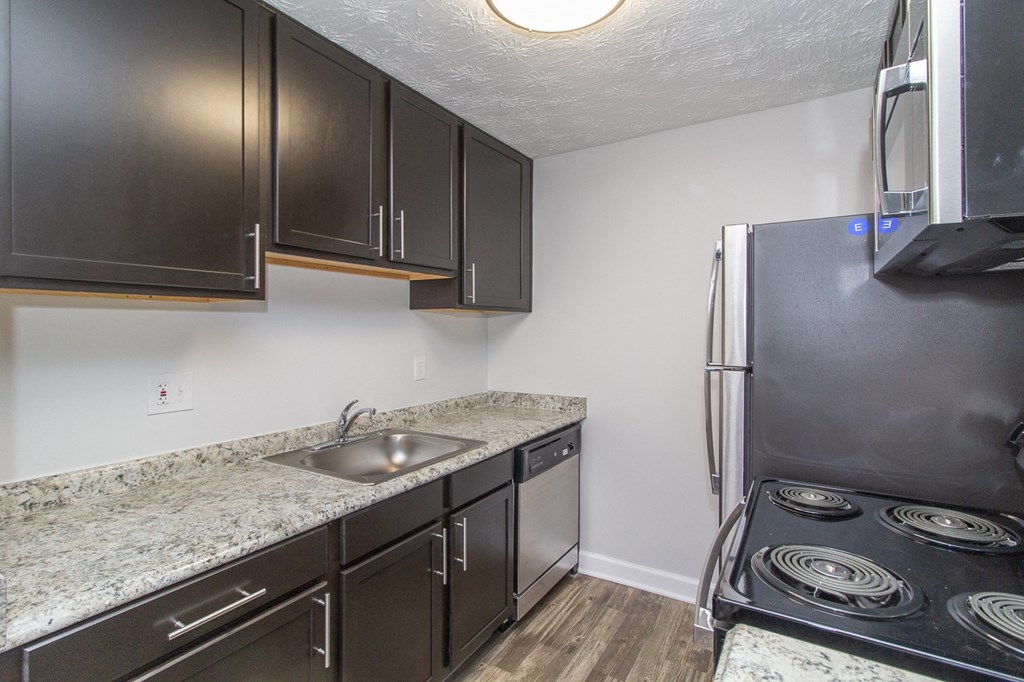 a kitchen with black appliances and granite counter tops and a stainless steel refrigerator