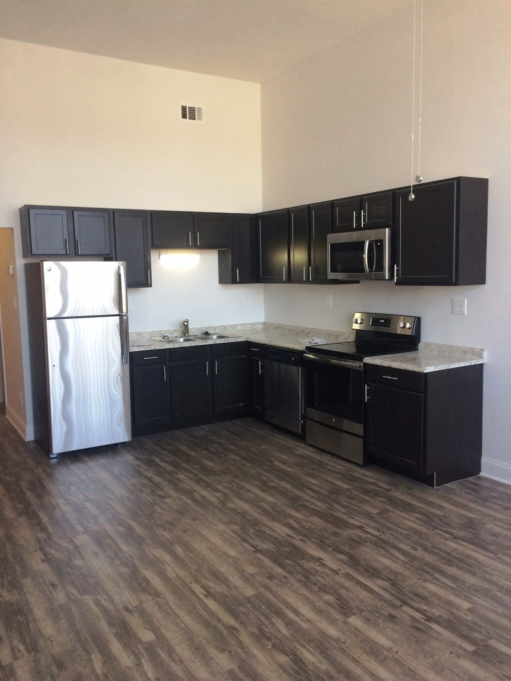 an empty kitchen with black cabinets and stainless steel appliances