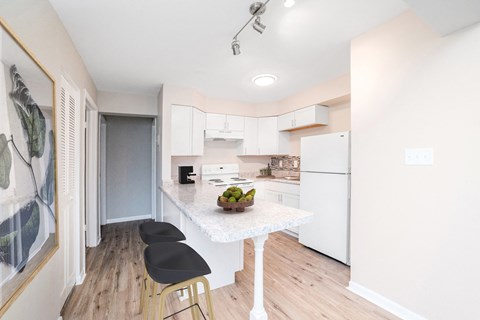 a renovated kitchen with white cabinets and a marble counter top
