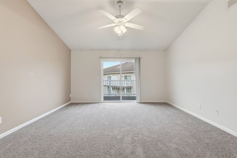 A spacious room with a ceiling fan and carpeted floor.