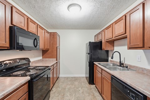 A kitchen with black appliances and brown cabinets.
