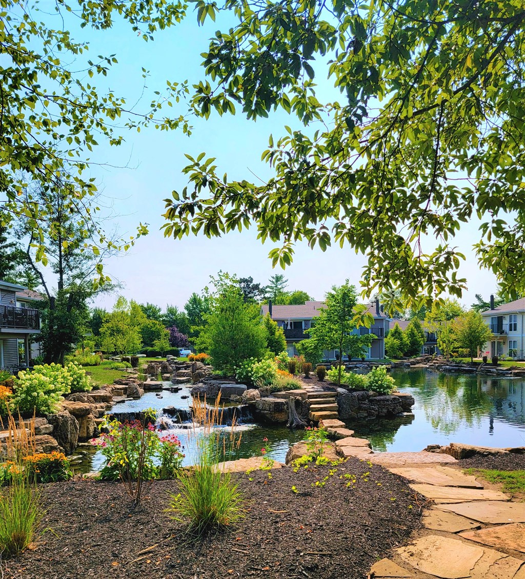 a garden with a pond and bridge in front of a building at Harpers Point Apartments, Ohio, 45249
