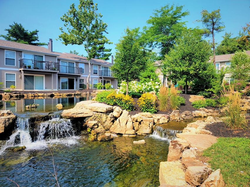 a pond with a waterfall in front of a building - Photo Gallery 1