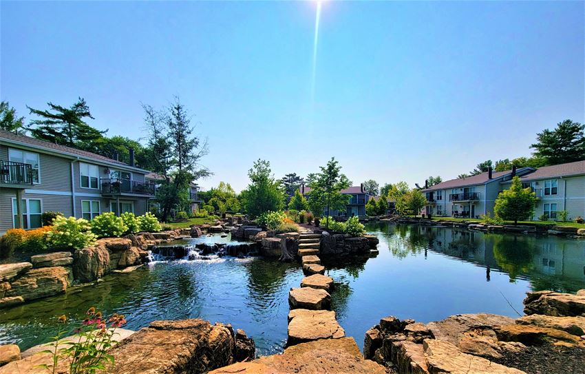 a pond with rocks and waterfall in front of an apartment complex - Photo Gallery