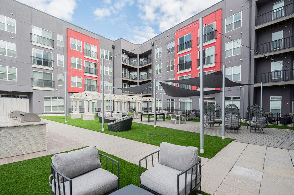 an outdoor area with chairs and a lawn in front of an apartment building