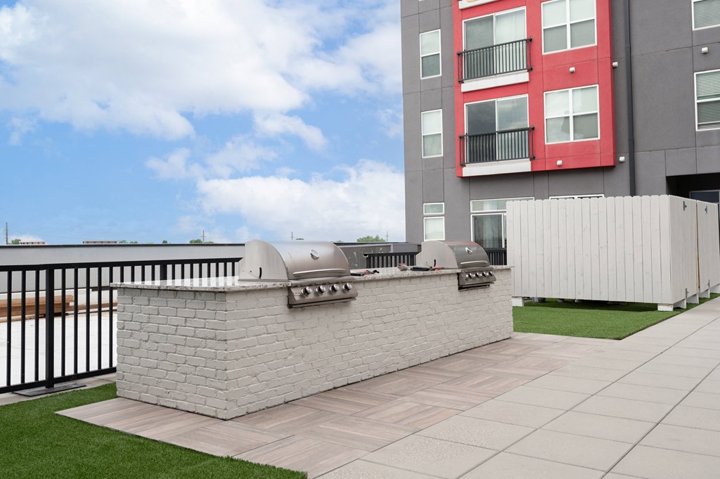 the outdoor patio of an apartment building with a barbecue grill