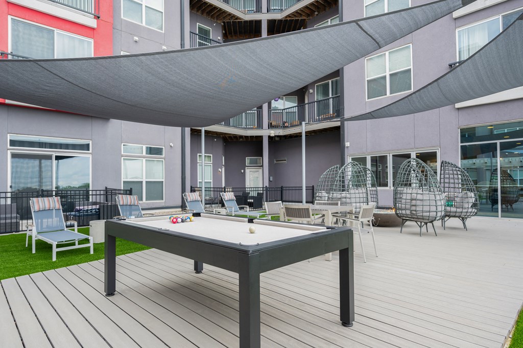 a patio with a pool table and chairs in front of a building