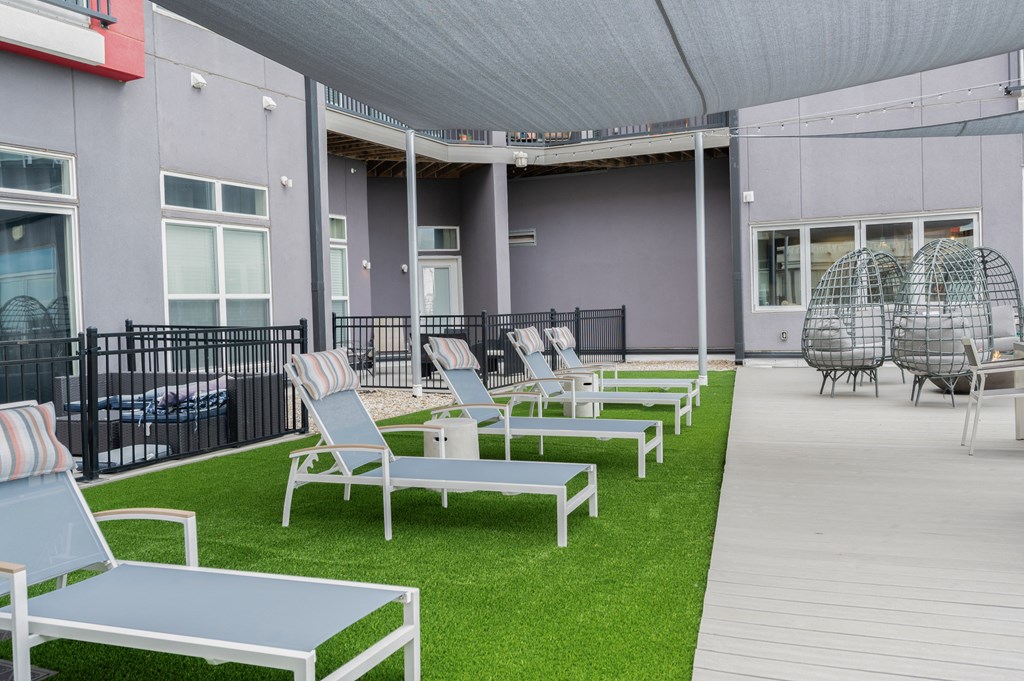 a row of lounge chairs and tables on the grass outside of a building