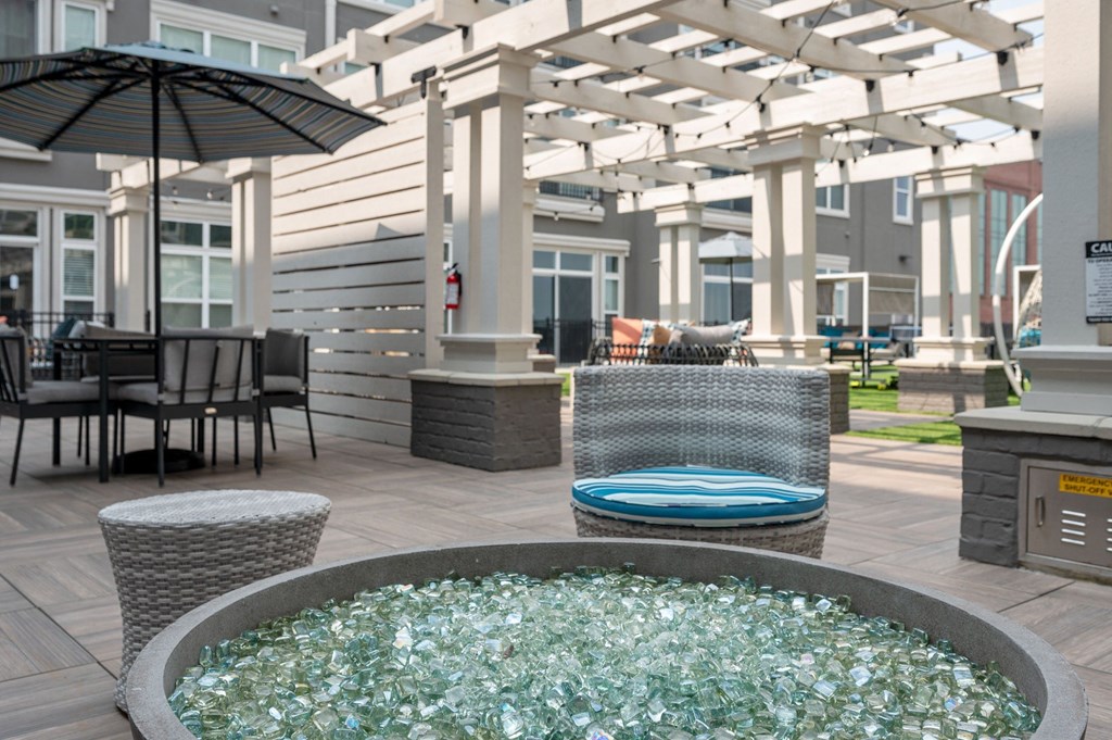 a patio with a fire pit and tables with umbrellas