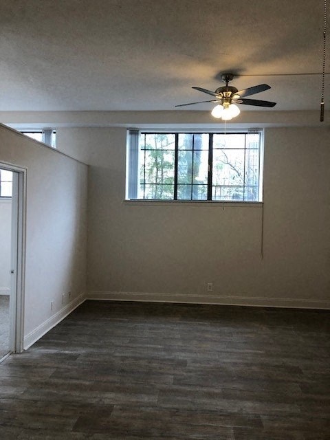 an empty living room with a ceiling fan and a window