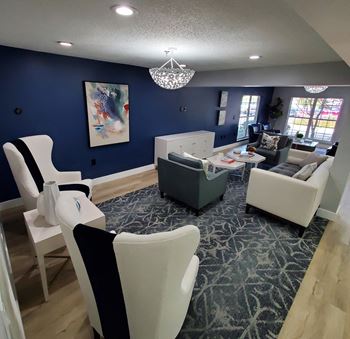 a room with blue walls and white chairs and couches