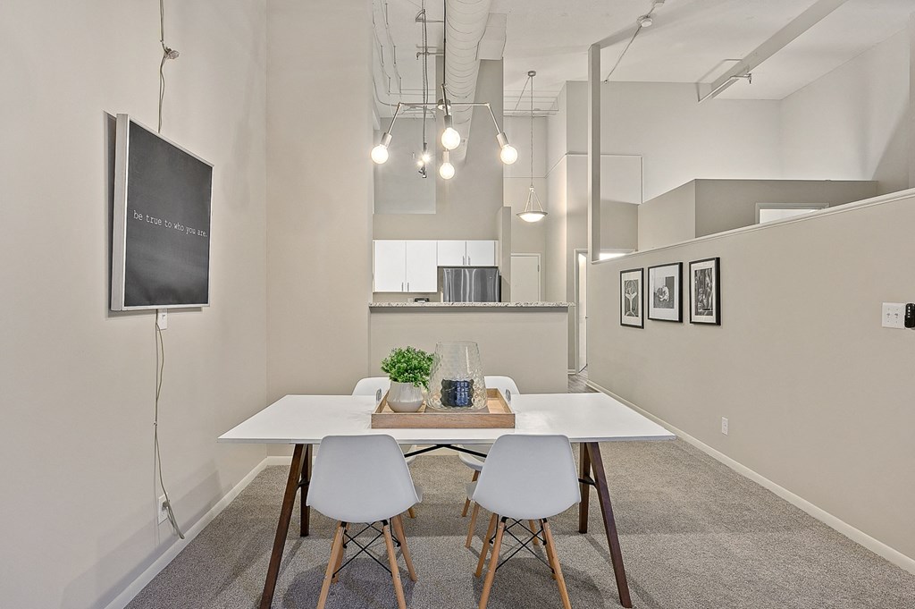spacious dining room with white table and chairs and kitchen in the background