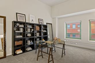 an office with a glass desk and a bookcase in a room with a window