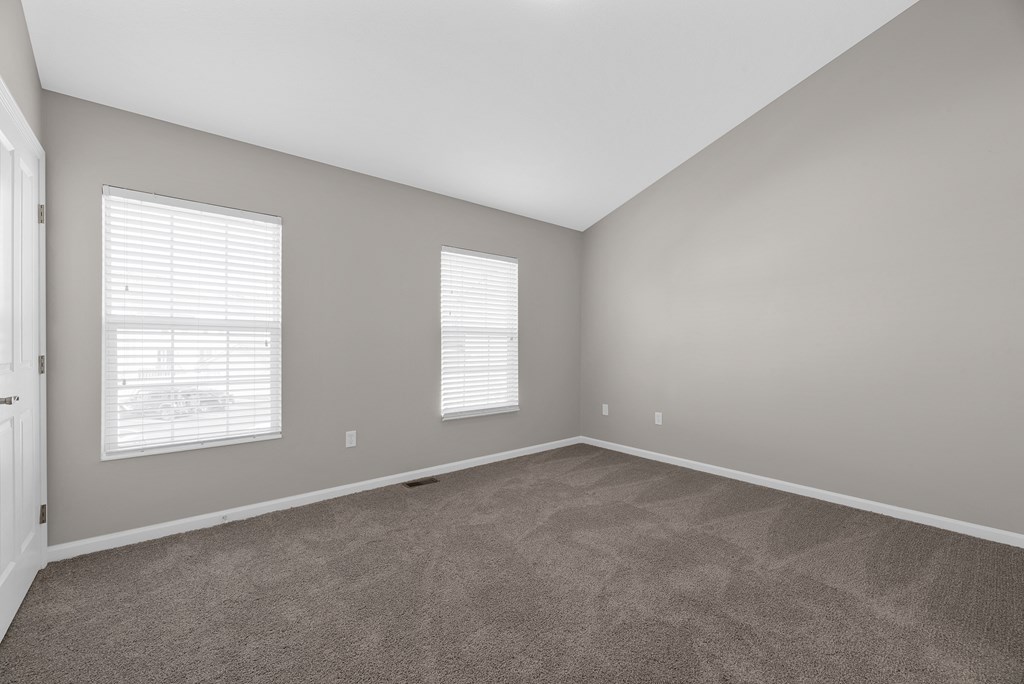 an empty living room with carpet and two windows at Traditions at Slate Ridge, Reynoldsburg, OH