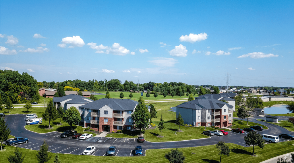 an aerial view of an apartment complex with a parking lot and a lake