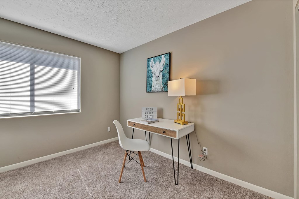 a desk with a chair and a lamp in a room with a window
