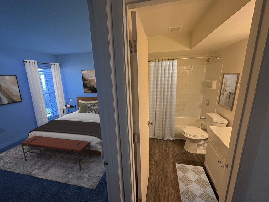 A bedroom with a bed, a bench, and a bathroom with a toilet and sink.