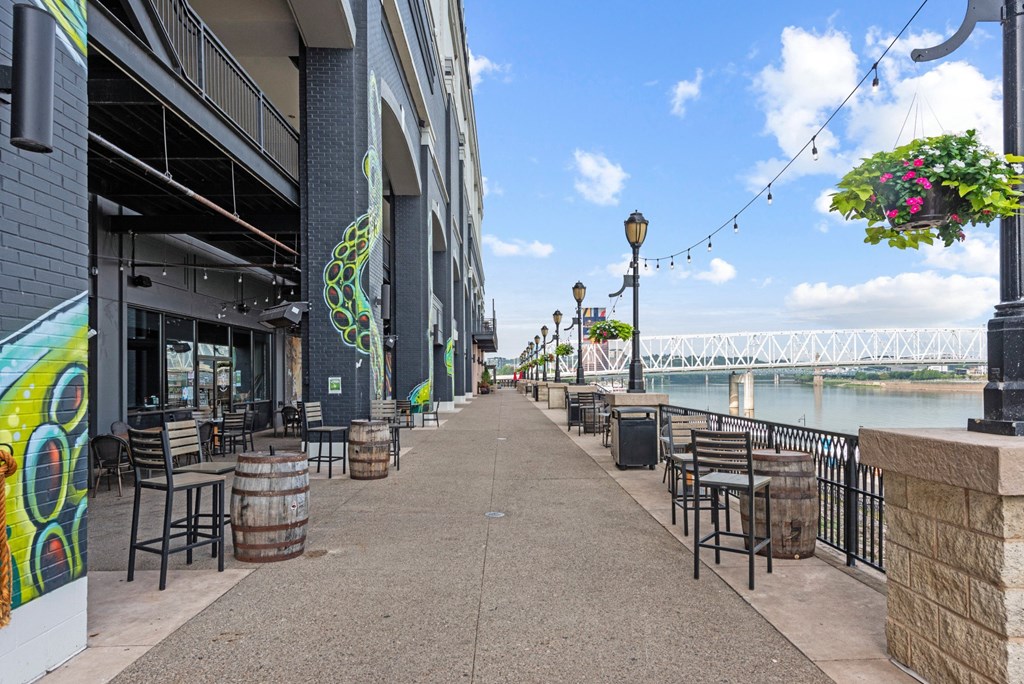 a sidewalk with tables and chairs near a river and a bridge at Monmouth Row Apartments, Newport, 41071
