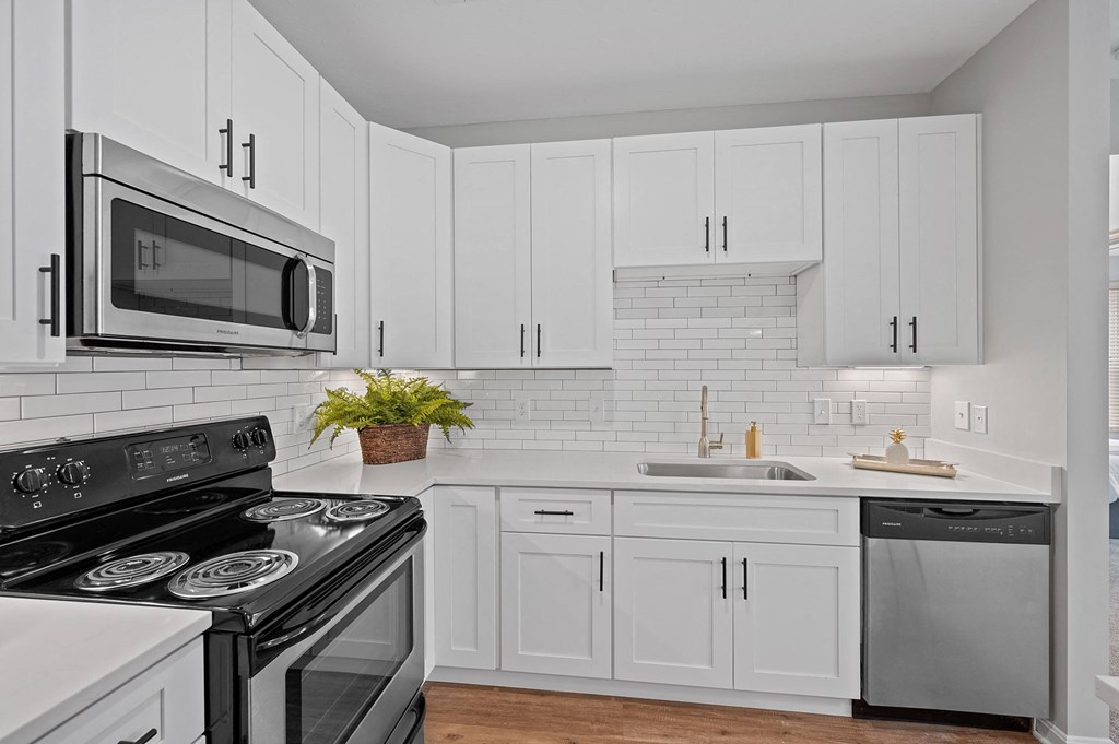 a white kitchen with black appliances and white cabinets at Monmouth Row Apartments, Kentucky