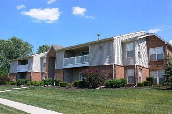 A row of apartment buildings with green lawns in front.