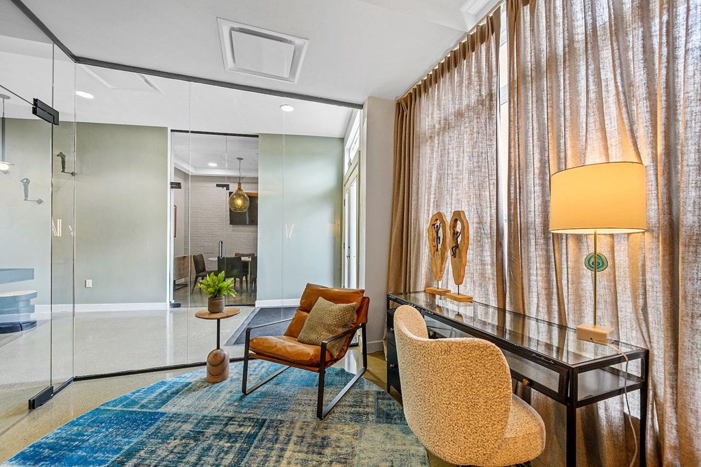 a living room with a desk and chairs and a large curtain