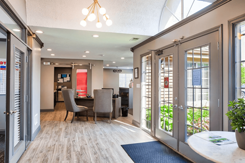 A modern office space with a glass wall and a wooden floor.