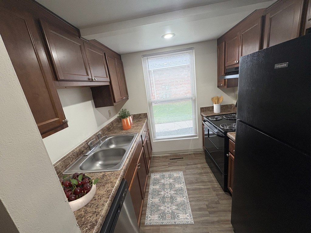 A kitchen with brown cabinets and a black refrigerator.