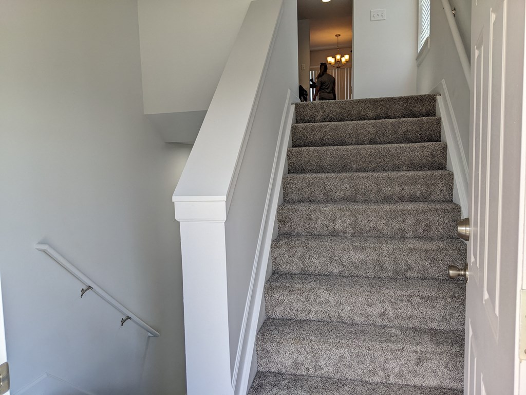 a view from the bottom of the stairs looking into the kitchen and living room