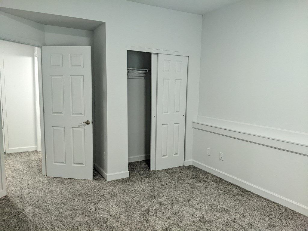 a bedroom with two closets and a carpeted floor