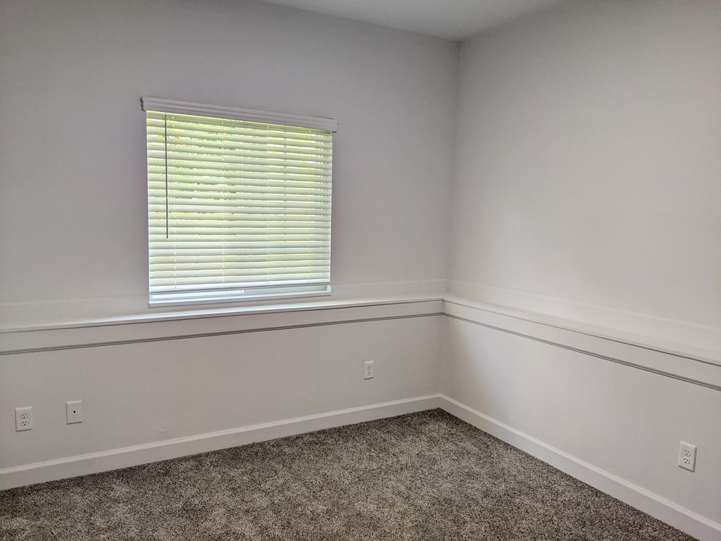 a bedroom with white walls and a window with a blind