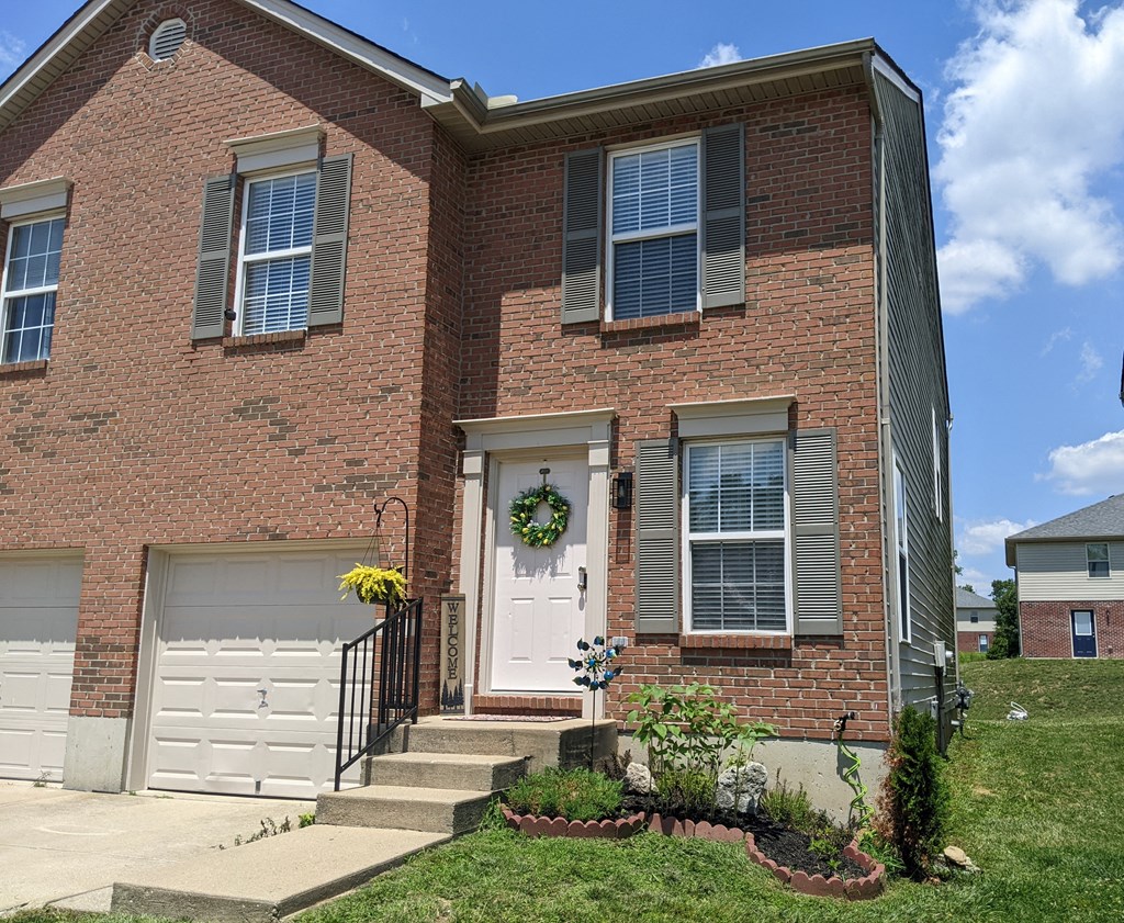 a brick house with a white door and white garage doors
