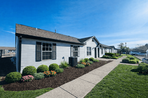 A white house with a brown roof and a grey front yard.