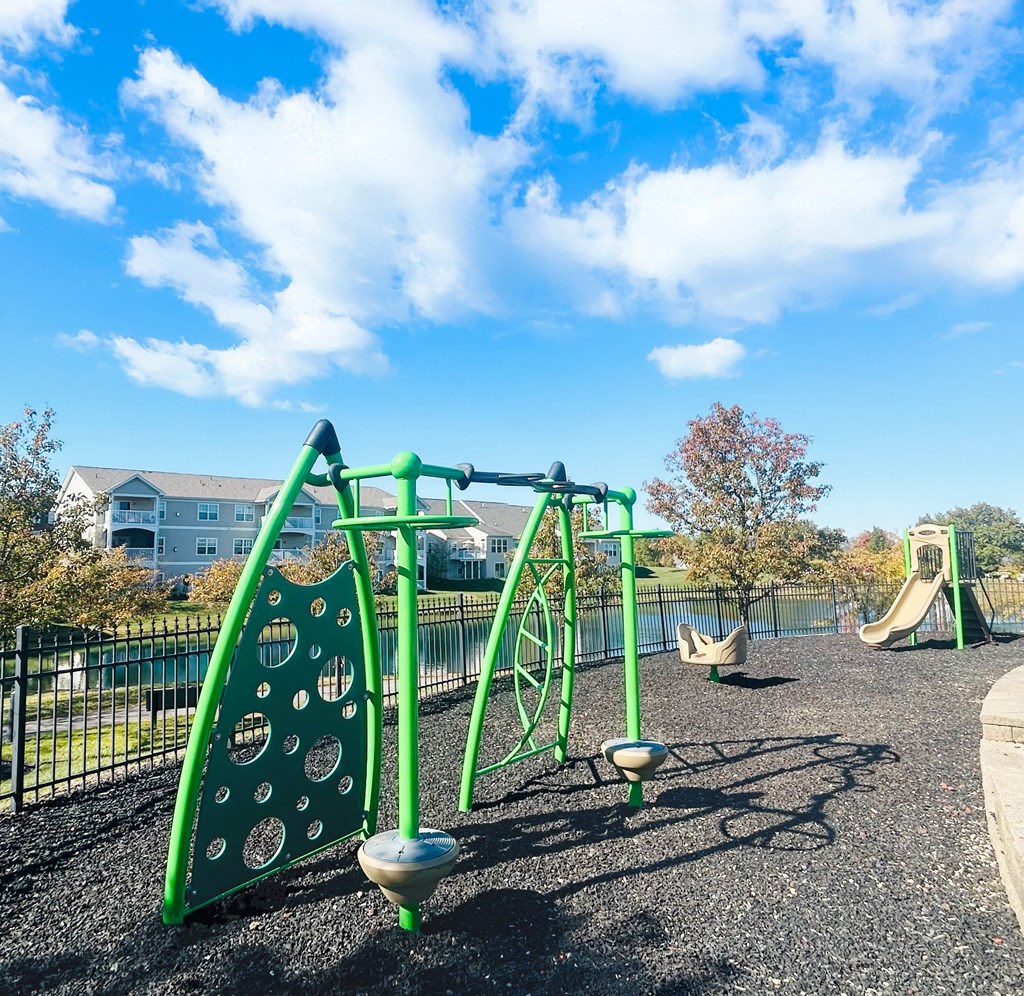 A playground with a green swing set and a slide.