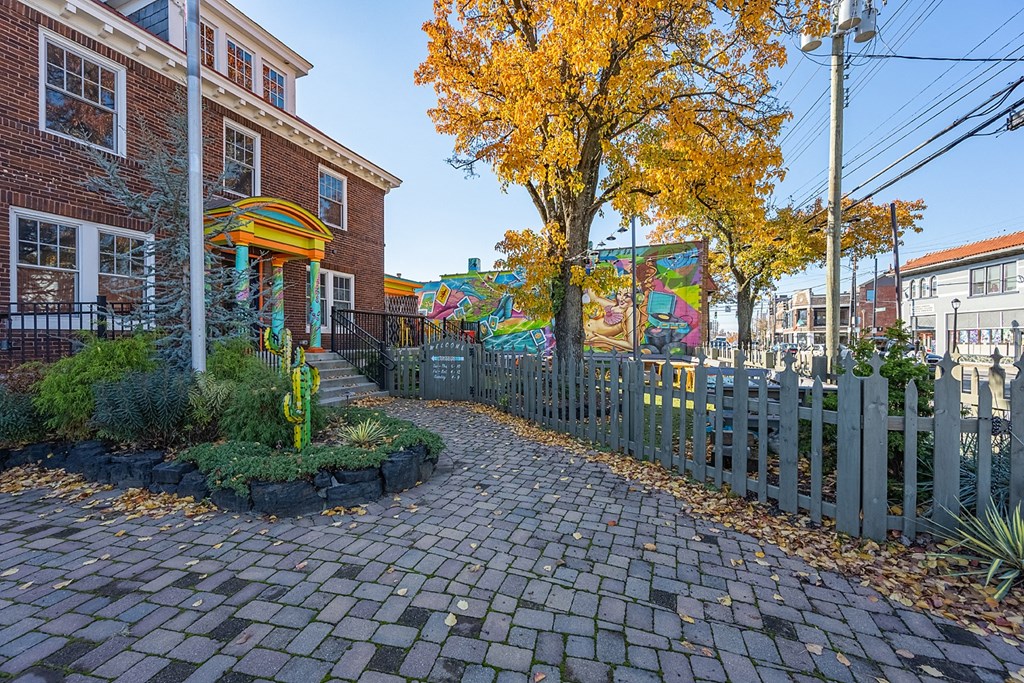 a path with a fence and a tree in front of a building