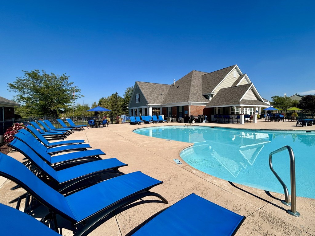 A pool with blue sun loungers and a building in the background.