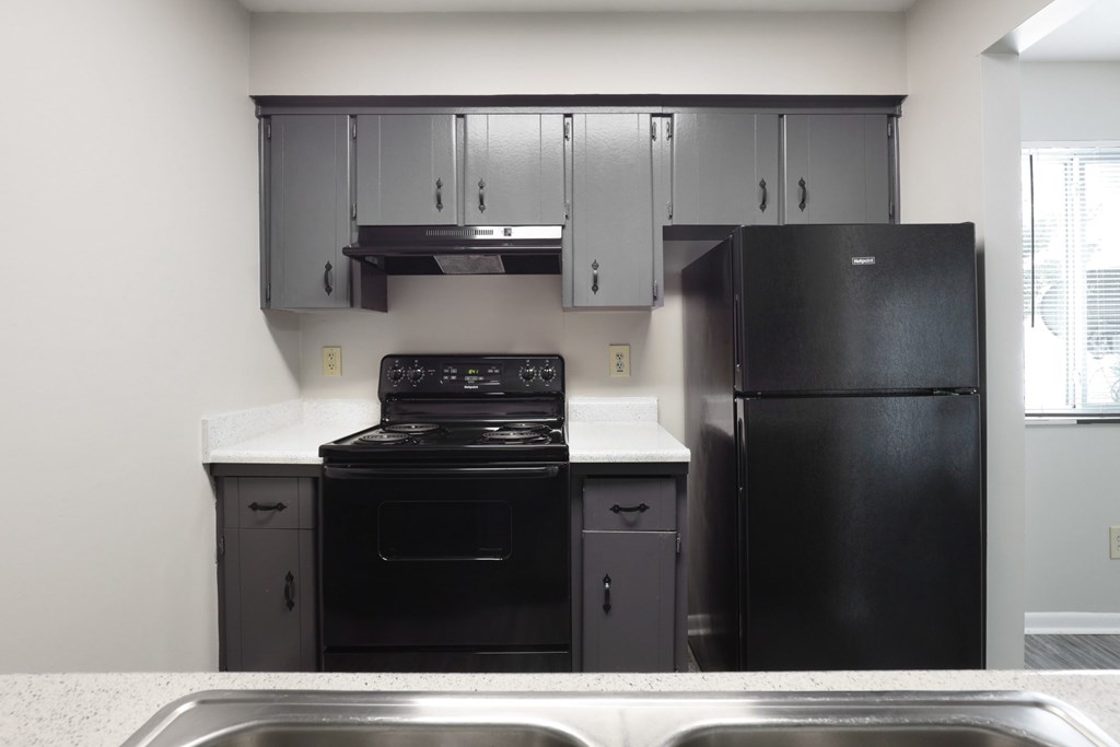 A black stove and oven in a kitchen with a black fridge.