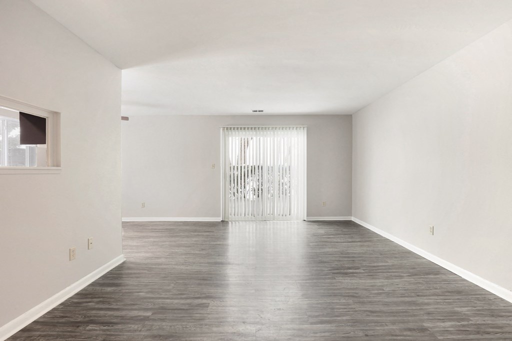A large empty room with a wooden floor and white walls.