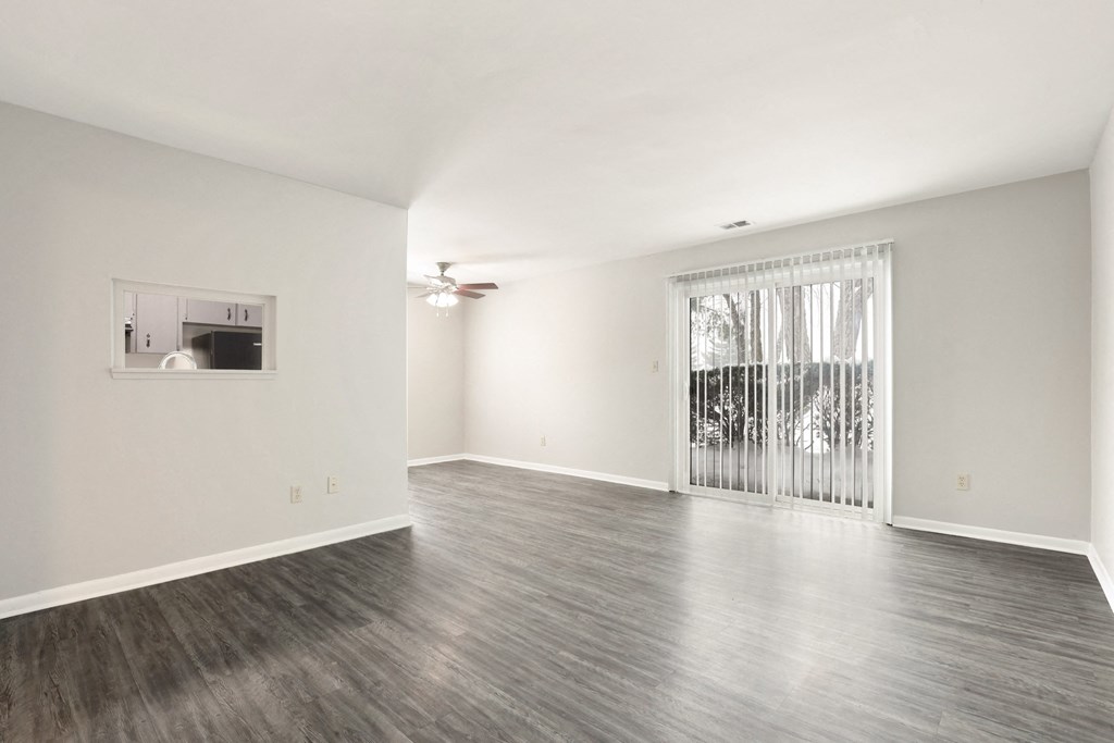 A spacious room with a sliding glass door leading to a balcony.