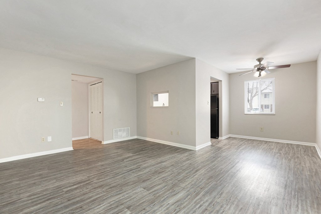 A spacious room with a ceiling fan and light wood flooring.