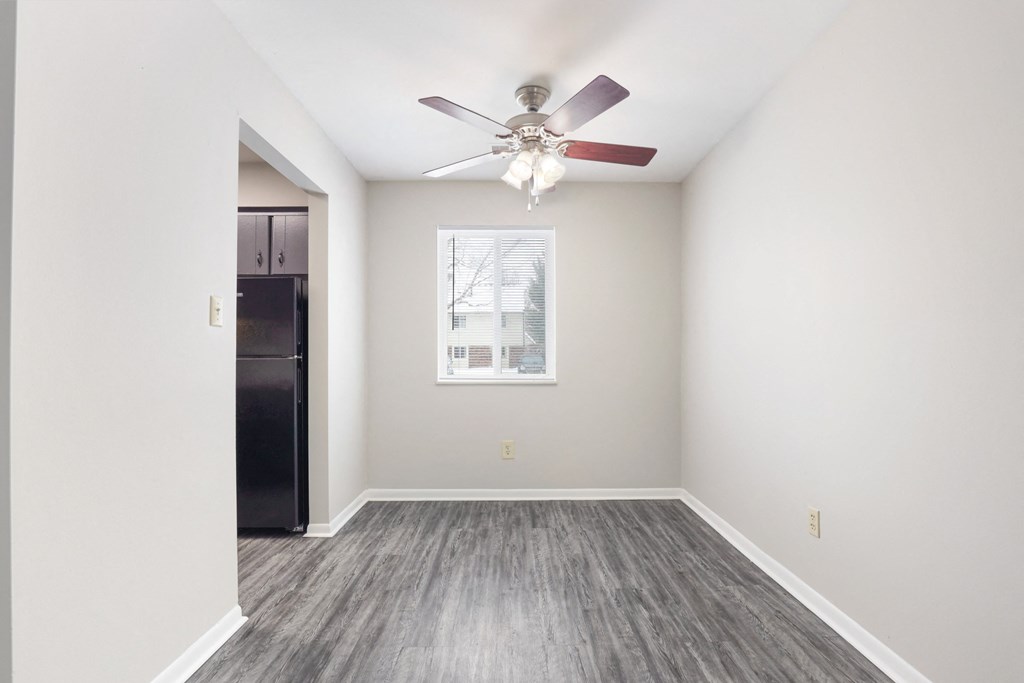 A room with a ceiling fan and a fridge in it.