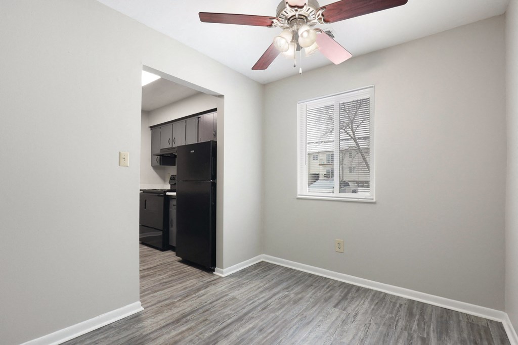 A room with a ceiling fan and a window with blinds.