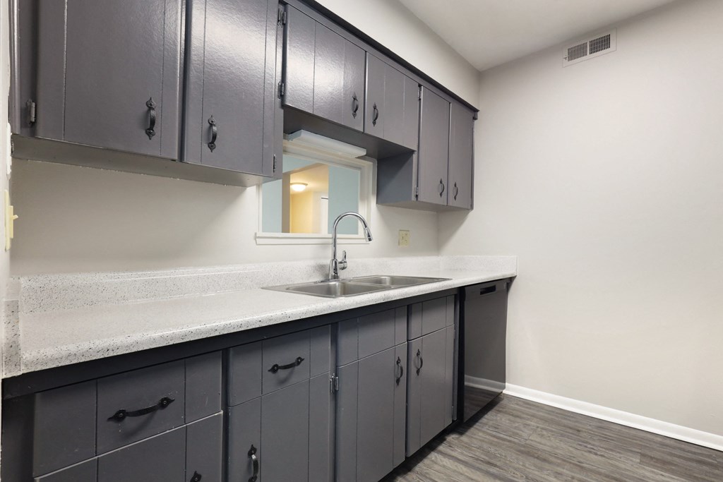 A kitchen with grey cabinets and a white countertop.