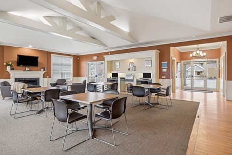 Community clubhouse with dining tables and fireplace lounge at North Central Village Apartments, Ohio