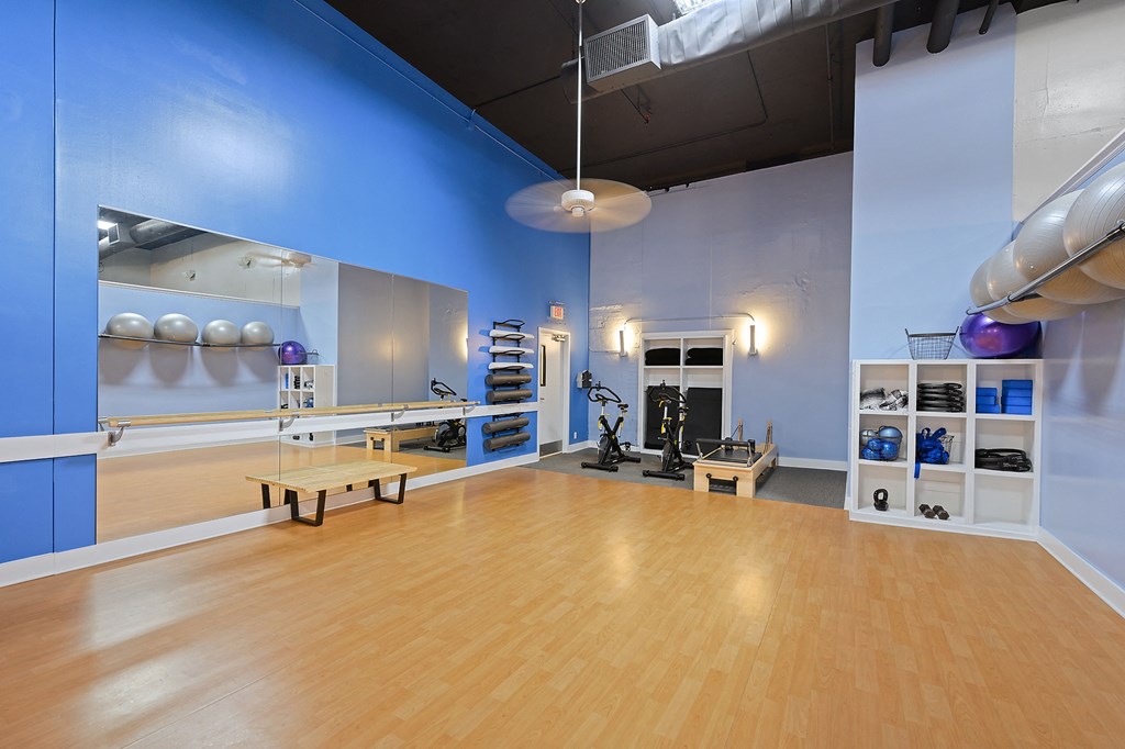 a gym with a wooden floor and a blue wall with weights and yoga equipment