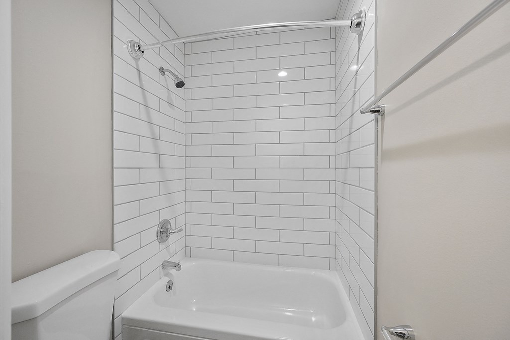 a bathroom with white subway tile and a white bathtub