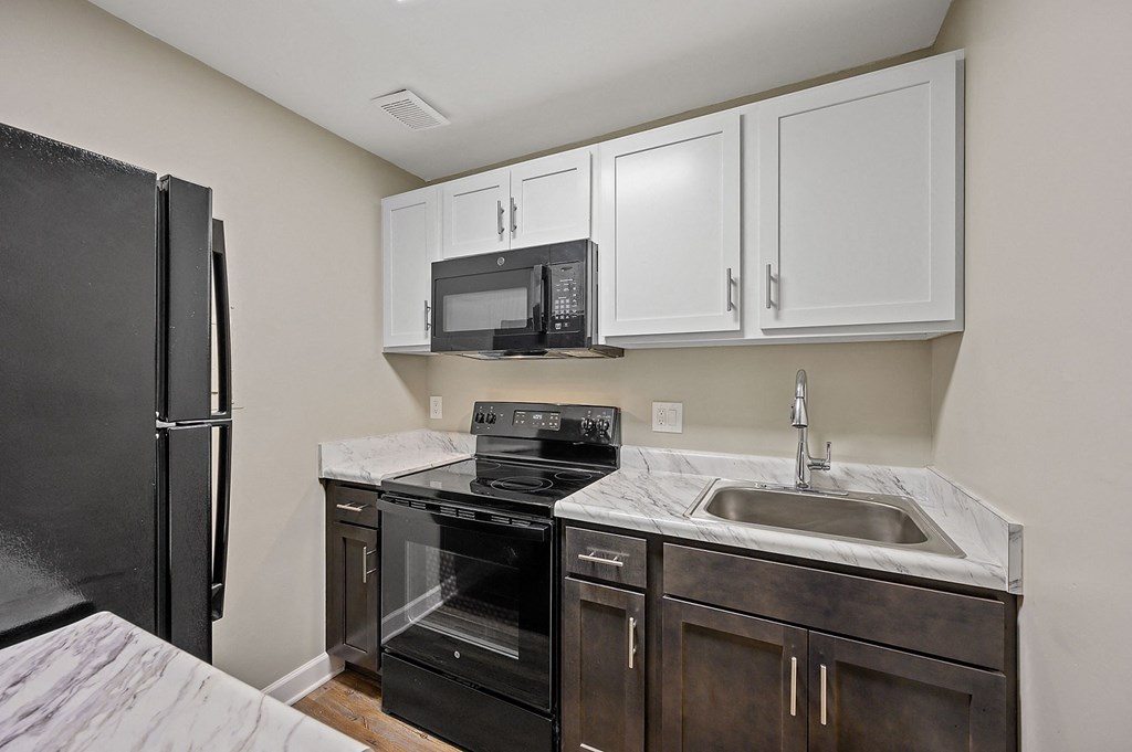 a kitchen with white cabinets and black appliances