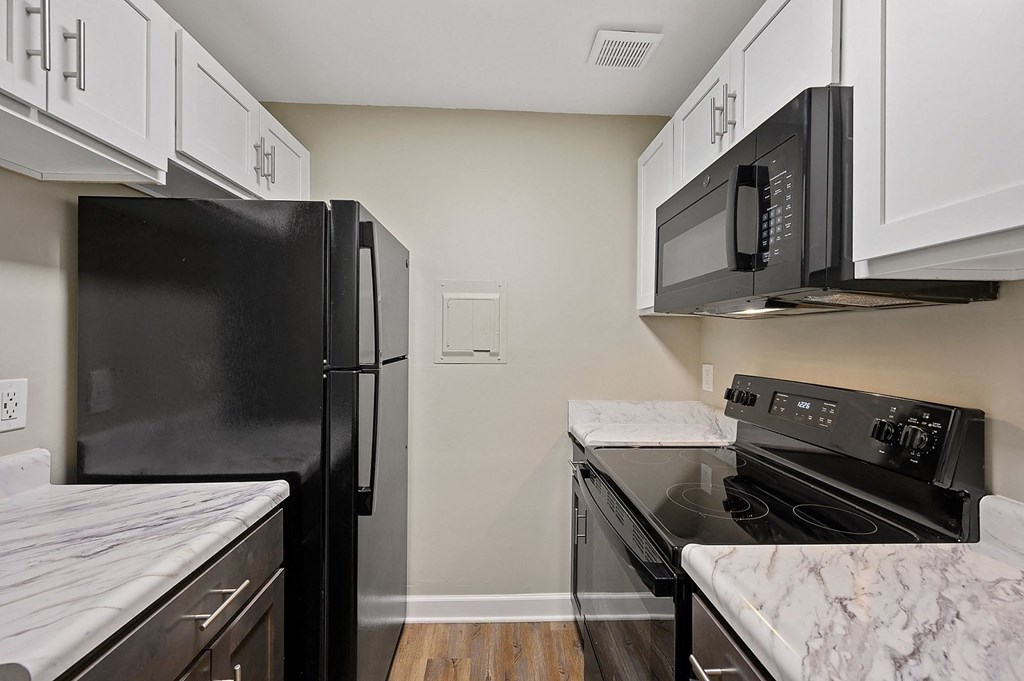 a kitchen with white cabinets and black appliances