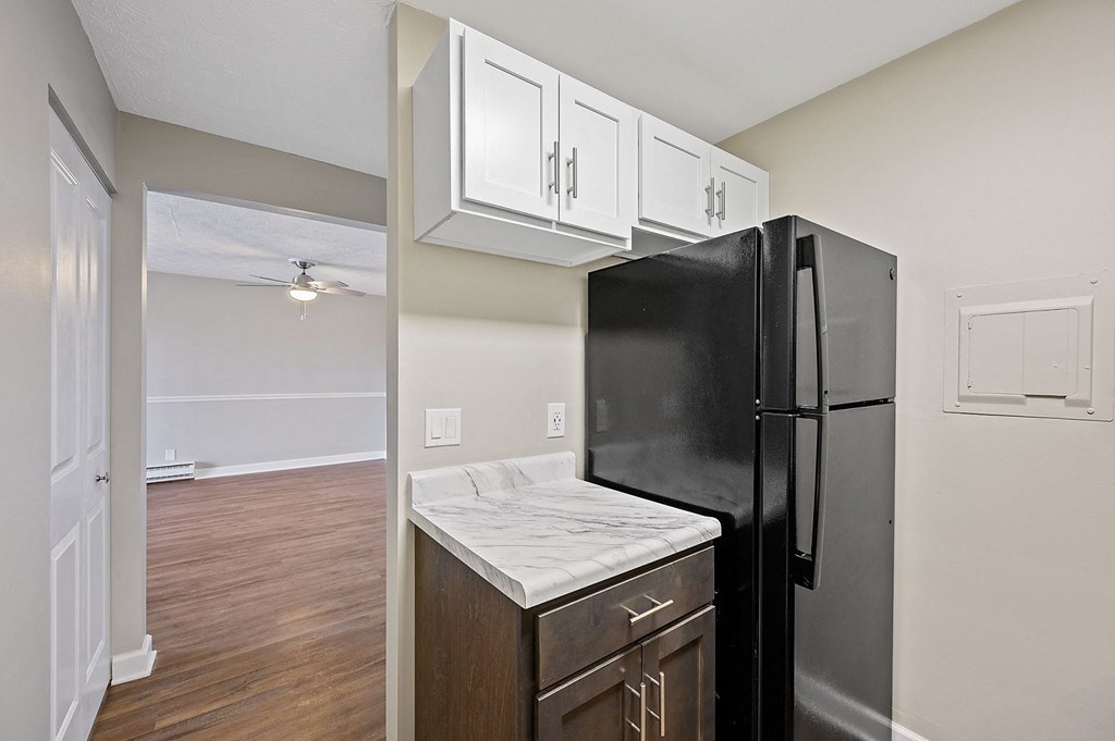 a kitchen with white cabinets and a black refrigerator