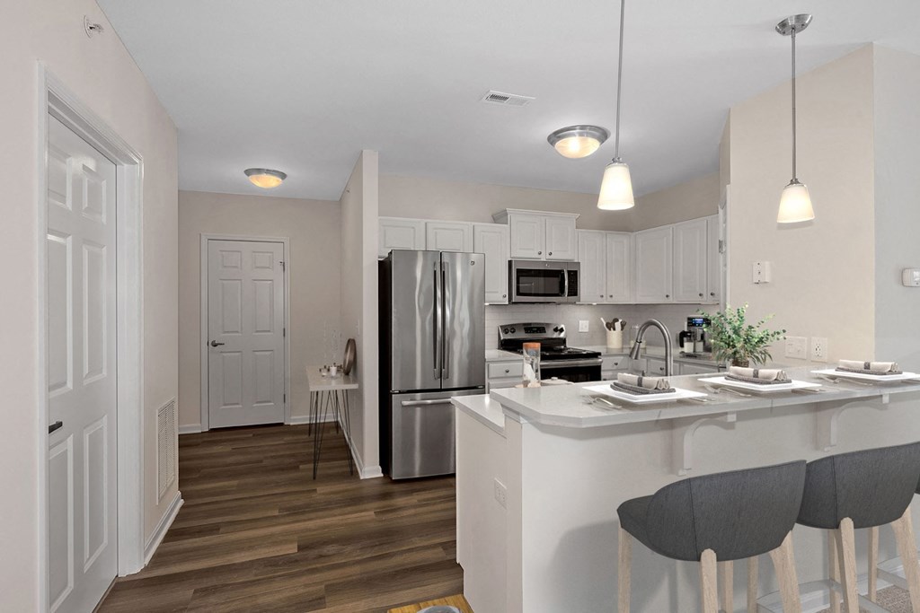 an open kitchen with an island and a stainless steel refrigerator